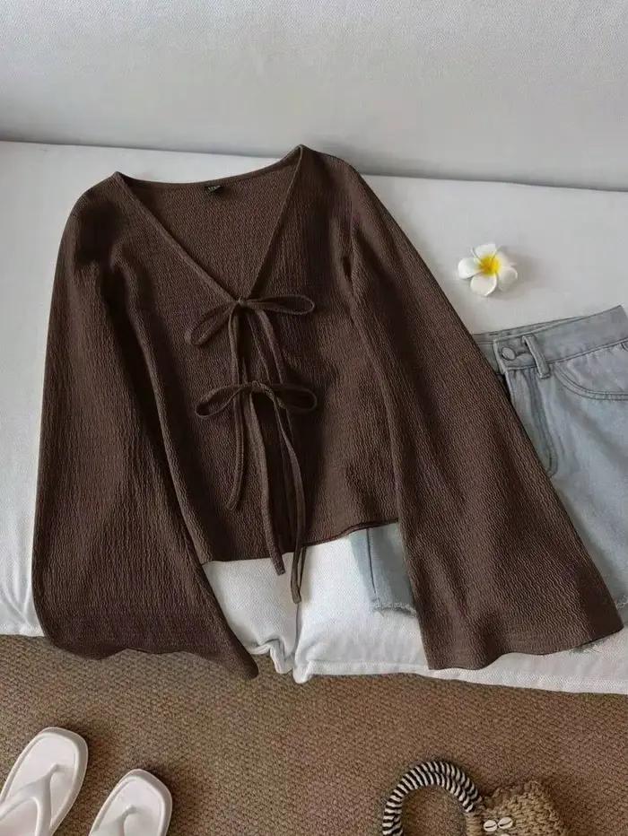 Cardigan pour femme en tissu texturé ondulé. Il présente un col en V, une ceinture à nouer sur le de
